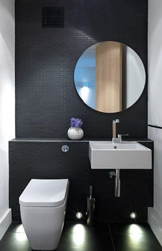 Design en noir en blanc pour une décoration WC avec du carrelage.  Sur le mur de la cuvette WC suspendu et du lave-main blanc un carrelage petits carreaux noir apporte un chic absolu à ces toilettes