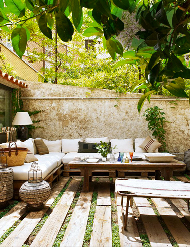 Salon de jardin en palette sur sol terrasse bois Salon de jardin en palette fabriqué pour une installation en L sur 2 murs de la terrasse en bois. Assortie, une table basse en palette dont le plateau plein est assemblé grâce à des tasseaux fixés par le dessous.