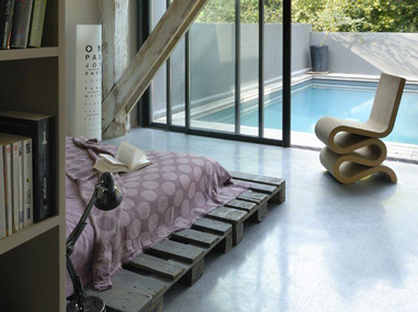 Lit fait de 4 palettes bois teintée gris et posées directement sur le sol pour une ambiance zen dans la chambre. Le débord des palettes sert de tables de nuit