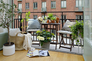 Aménagement d'un balcon en prolongement du salon pour compenser la petite surface. Une part belle est faite aux matériaux et couleurs naturelles avec un salon de jardin en teck, panier en paille et gros coussins de chaises