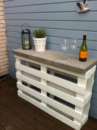 un bar pour le jardin fabriqué avec une seule palette bois peinte en blanc pour fabriquer le pied sur lequel sont posé des carreaux en béton pour le plateau 