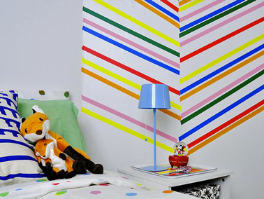 decoration murale dans chambre avec du Masking tape de couleur Décoration murale dans une chambre d'enfant avec des rubans adhésifs de couleurs détachables à poser en épi sur toute la hauteur du mur près du lit