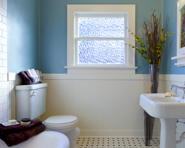 Dans une salle de bain rétro de couleur blanche, une peinture bleue en contraste avec le soubassement blanc c'est tonique. Une petite touche de prune avec le linge de toilette et la déco de la salle de bain reprend des couleurs !