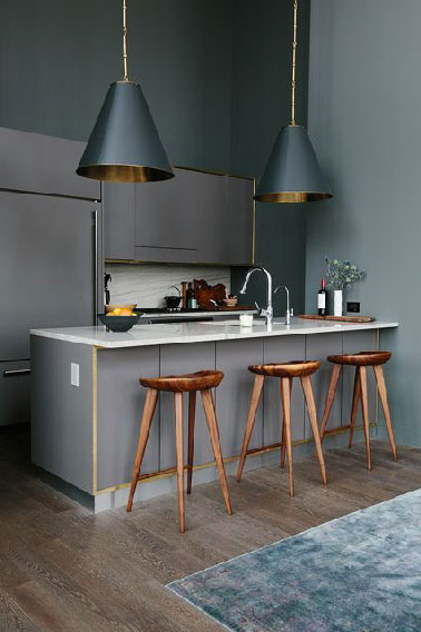 déco cuisine entièrement grise en trois tons. meubles gris souris intégrés dans mur peint gris anthracite. Au dessus du bar souligné de baguettes de laiton, 2 big suspensions avec abat-jour cuivre