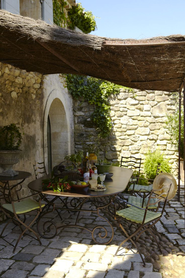 Pergola terrasse en brande de bruyére installée devant maison provençale pour protéger la terrasse du soleil avec salon de jardin