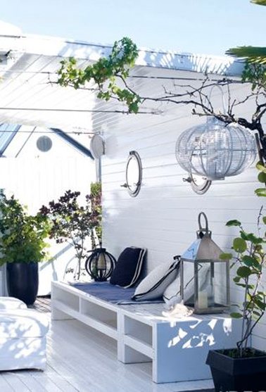Pergola sur terrasse ambiance ile de Ré blanc et bleu avec toit en plaque PVC ondulé et transparant. Le ban est construit sur mesure avec dalles béton peint en blanc