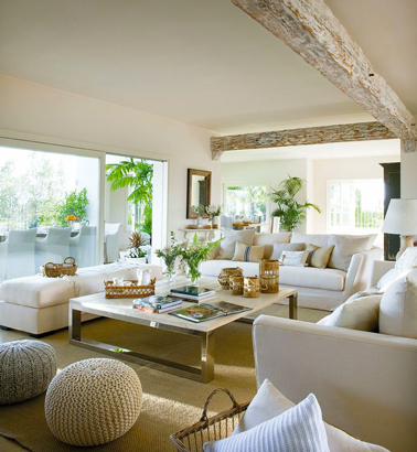 Dans un salon moderne aux larges baies vitrées, seul le vert tendre des plantes d'intérieur pour relever la couleur lin et blanc des murs, du sol et des canapés pour un résultat plein de fraicheur