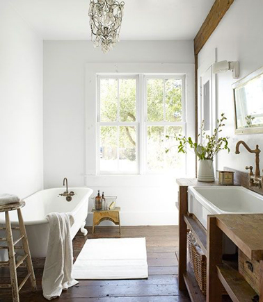 Style rétro dans cette salle de bain avec un meuble vasque et rangement en teck, baignoire et lavabo en céramique blanche agrémentés d'une robinetterie en laiton