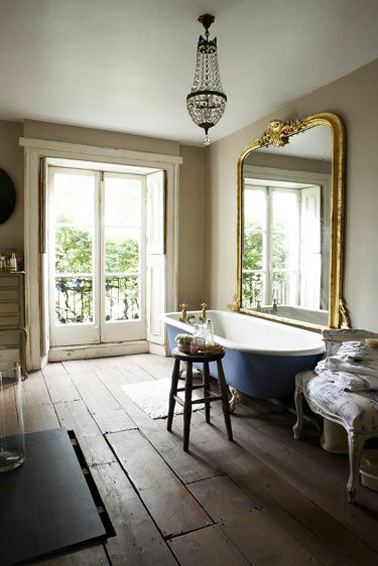 Dans une salle de bain rétro, un grand miroir ancien, un fauteuil de style donne tout de suite le ton ! Ajoutez une baignoire sur pieds avec une coque de couleur bleu pour contraster avec une sol en parquet l'harmonie sera parfaite
