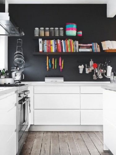 L'élégance du noir sur le mur du fond d'une cuisine blanche agencée en L. Pour compléter l'ambiance design, un plan de travail en Corian gris perle, le tout sublimé par l'apport chaleureux du sol en parquet chêne grisé