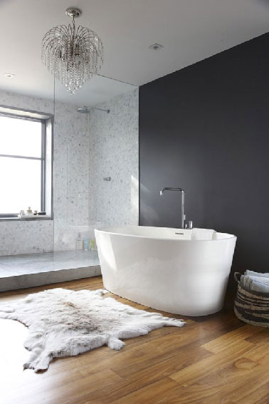 La rénovation d'une salle de bain dans une maison ancienne qui a permis de d'installer une estrade pour y placer la douche italienne. Le parquet restauré et vitrifié apporte une touche chaleureuse à l'ambiance où gris et blanc dominent.