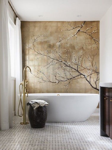 Une déco de salle de bain digne d'un espace consacré au bien-être avec au dessus de la baignoire blanche une fresque réalisée sur un mur de carreaux de verres peint dans des tons mordoré et brun. Le panier en osier et le robinet baignoire îlot complètent à ravir l'ambiance de cette salle de bain hyper zen
