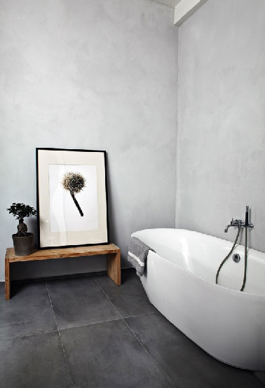 Décoration minimaliste, matériaux bruts et couleurs neutres pour cette salle de bain résolument zen. Au sol un carrelage grands carreaux de 40X70 cm gris anthracite, au mur un béton gris perle mettent le focus sur les formes généreuses de la baignoire îlot