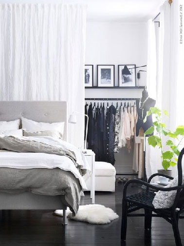 Dans une chambre avec un dressing ouvert, un rideau de voile blanc sert de séparation légère et esthétique
