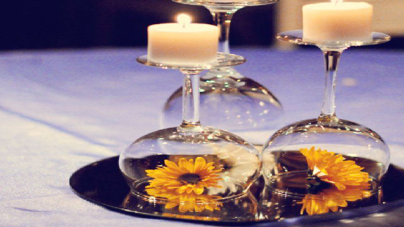 DIY déco pour faire un centre de table de Noël avec des accessoires simples : verres à pied, assiettes, bougies et des fleurs assorties aux couleurs de la table