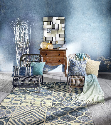 Pour une ambiance plus terre à mer, le bois est également présent en contraste dans le nouveau catalogue printemps/été Helline autant dans les fauteuils de relaxation en rotin  que les tables basses à coordonner par exemple avec un tapis bleu délavé, une couleur tendre qui s’entremêle à des motifs blanc cassé.