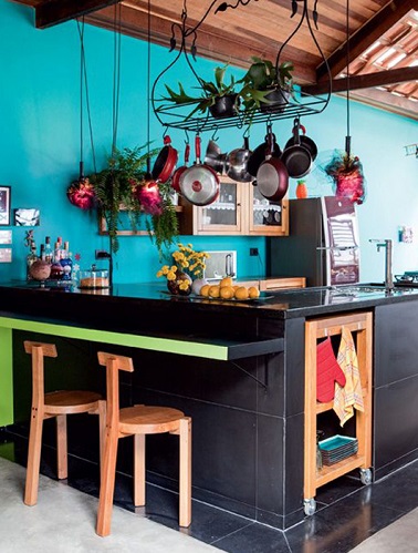 Cette cuisine bleue turquoie rappelle le bleu des îles et des vacances. Les couleurs sont très présentes par petites touches. Du vert anis sur la tranche de l'îlot, du rouge dans les accessoires et quelques pièce en bois renforcent cette déco évocatrice de voyages lointains. L'îlot central gris profond offre le contraste et la modernité à cette cuisine bleue.