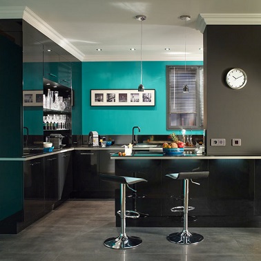 Cette cuisine bleu turquoise doit son atout charme à son pan de mur turquoise. Avec un sol gris béton et des meubles très contemporains noirs et laqués, le bleu turquoise saute aux yeux. Il donne une profondeur supplémentaire à cette cuisine américaine très contemporaine et apporte la touche originale chic.