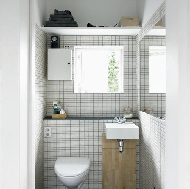 Des toilettes aux allures de spa norvégien. Cette déco idéale pour les petits espaces affiche de petits carreaux blancs comparables à ceux d'un papier millimétré. Vient s'ajouter à cette ambiance, un morceau de bois clair sous la vasque pour apporter la touche nature nécessaire à toute ambiance scandinave aux toilettes. 