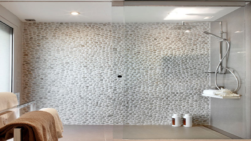 Du carrelage galets gris sur un mur de la douche italienne, du béton ciré gris clair sur un autre, voilà une douche qui donne des idées déco pour la salle de bain