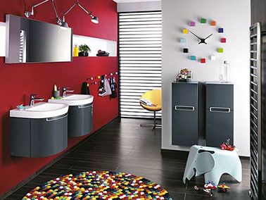 Des accessoires de salle de bain de couleur flashy apportés avec modération dynamisent le mur rouge intense et le gris anthracite des meubles sous vasque et les placards gris anthracite de cette salle de bain qui ne manque de pep’s. Accessoires multicolores Tapis Cosy