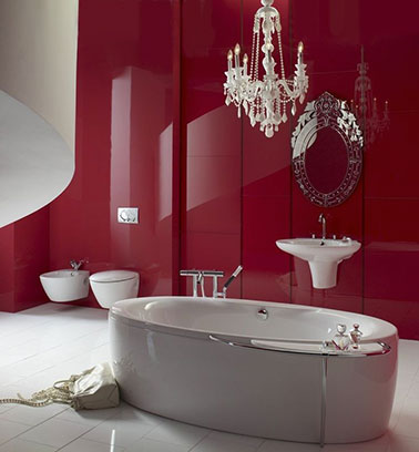 La salle de bain rouge laqué joue avec les éléments du baroque et du moderne. La baignoire blanche aux formes épurées et les vasques suspendues au mur rouge s’allie parfaitement. Un équilibre est instauré.  