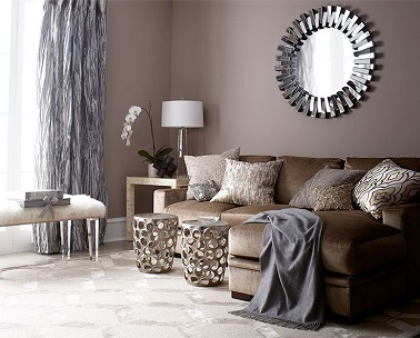 Chaleur et design se conjuguent dans ce salon couleur taupe et blanc Un salon lumineux à souhait grâce à la couleur taupe des murs contrastée par le sol blanc. Le canapé marron et les accessoires rideaux et plaid gris s'accordent à l'ambiance cocooning de ce salon. Le miroir et les petites tables d'appoint en métal donnent un côté plus tendance à toute la pièce.