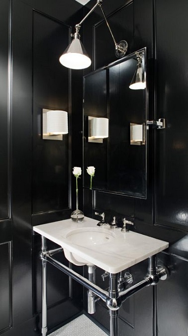 Cette petite salle de bain mise sur le duo noir et blanc pour un effet chic. Loin d'écraser la pièce, les murs noirs font ressortir les éléments qui composent la salle d'eau. Le meuble vasque est d’ailleurs mis en valeur tout comme l’espace disponible en dessous de ce dernier. La lumière tamisée quant à elle se charge d’achever cette déco tendance.