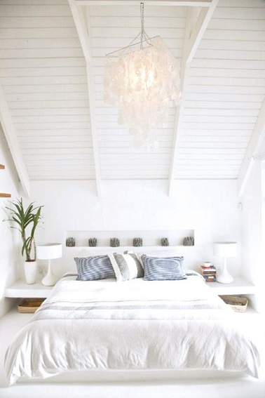 Sous un sublime plafond en lambris, une déco de chambre qui s’anime de touches de vert et bleu pour magnifier la blancheur immaculée qui règne dans la chambre. A noter, la tête de lit composée de large casier décoré de bougies verte alignées sur la largeur du lit 