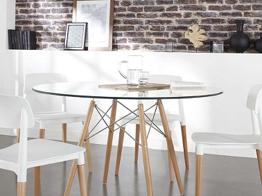 Une déco rétro scandinave ancrée dans la modernité s’invite autour de la table de cette salle à manger. Des pieds en hêtre et un plateau rond en verre transparent composent la table tendance au premier plan assortie à des chaises dans la même gamme. Le mur en briques apparentes de la pièce quant à lui rappelle la grosse pomme et ses lofts industriels chics.