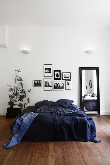 Un lit au centre de la pièce, un mur d'une blancheur immaculée, un miroir posé, quelques cadres et une plante, le décor minimaliste de cette chambre parentale laisse rêveur. 