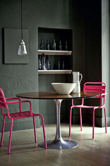 Les couleurs sombres dans la cuisine et on les aime pour  l'ambiance intime qu'elles dégagent. Sur les murs de cette cuisine, une peinture couleur taupe  préserve l’authenticité des murs anciens. La forte de cette peinture intense est mise en contraste avec le rose flashy des chaises autour de la table de verre. Couleur Peinture Little Greene