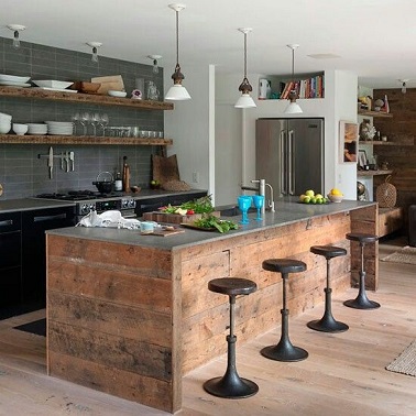 cuisine au charme industriel avec des meubles chinés Un esprit industriel brocanté règne dans cette cuisine. Le plan de travail en acier se conjugue à merveille avec la structure en bois brut qui le soutient ainsi que les tabourets chinés en métal. Du côté des fourneaux, la crédence en carrelage gris et les meubles noirs apportent la touche industrielle moderne. Les étagères en bois brut au dessus de l’évier rajoutent un côté authentique et récup’ à la pièce. La vaisselle blanche exposée sur ces dernières fait directement référence aux suspensions vintages blanches disposée à la même hauteur. Une harmonie de styles et de déco pour une cuisine indus’ bien équilibrée !