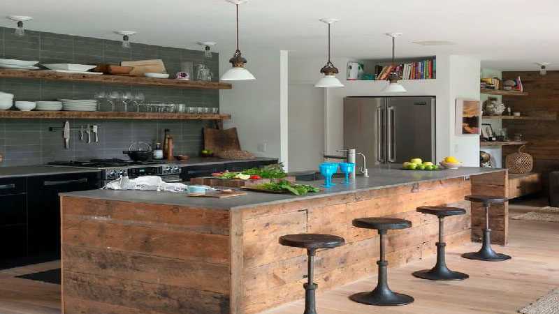 Dans une cuisine esprit industriel se mélange matériaux design en bois, inox comme le plan de travail, des murs brut style loft en briques ou pierres apparantes