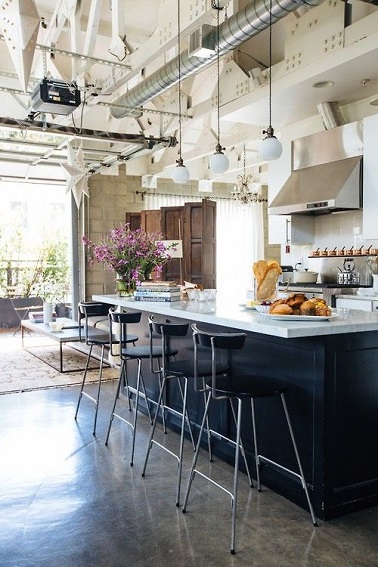Un design moderne industriel investit cette cuisine. L’îlot noir se marie à merveille avec le plan de travail blanc laqué et les mange-debout pour un coin repas moderne. Néanmoins, l’aspect industriel pur se joue plus vers le plafond dont la structure métallique apparente appuie le côté usine de la pièce. Les trois luminaires suspendus rajoutent, eux, la petite touche vintage chic qui achève cette déco de loft tendance !