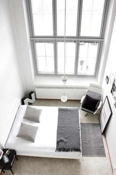Le minimalisme joue avec le noir et blanc dans cette chambre. Exploitant l’ensoleillement maxi, priorité est donnée aux meubles et éléments de déco au sol pour mettre en avant la belle hauteur sous plafond