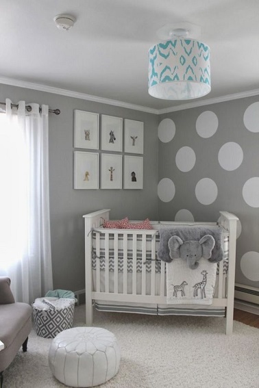 Idée peinture de la chambre fille, le gris s’affirme à 100 % ! Tous les murs de cette pièce se voient recouverts par cette couleur neutre et graphique. Des ronds blancs peints en contraste sur l’un des murs jouent avec le côté géométrique rappelé par les cadres blancs au dessus du lit. Seuls deux coussins dans le petit lit de bébé et la suspension apportent des touches de couleurs discrètes dans cette chambre.  Des rappels aux animaux de la savane, éléphants et autres girafes, donnent le thème de cette chambre cosy grâce à son tapis molletonné blanc.  