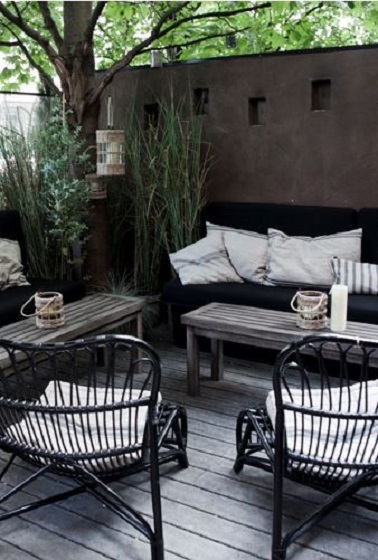 Style contemporain sur une terrasse en bois patiné Une terrasse qui adopte le bois patiné pour créer son ambiance. Dominant un jardin zen, le sol en bois grisé s’accorde avec le salon de jardin noir résolument moderne