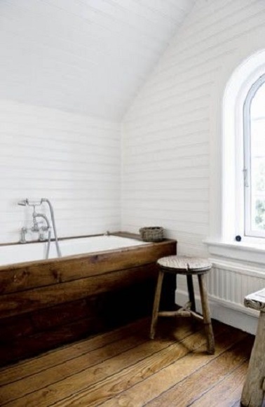 Déco minimaliste dans une salle de bain de style scandinave ou le bois exprime son caractère chaleureux autour de la baignoire et des murs d’un blanc immaculé.