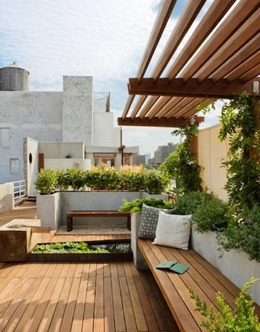 Une terrasse en bois juchée sur les toits qui mise sur le teck en total look pour planter le décor. Sol, et large banc aménagés avec les mêmes lames de teck clair répondent au mini auvent fait de poutres bicolore