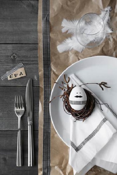 Déco rustique chic pour Pâques, une bonne idée pour mettre sa table dans la tendance. La déco de Pâques ne répond à aucune règle. Alors si votre préférence ne va pas à la couleur, vous pouvez très bien opter pour une déco plus en retenue et sobre. Cette table en est la preuve avec son style rustique sans couleur si chic. Pour contraster avec le bois gris et brut de la table, un chemin de table marron clair vient apporter un peu de luminosité et de relief à cette déco de Pâques très épurée. De jolies plumes blanches et légères viennent d’ailleurs soutenir le verre à pied pour donner un côté aérien à la table. Et pour apporter de la modernité, cette déco adopte des serviettes imprimés avec des rayures noires qui se marient élégamment avec celles qui ornent l’œuf peint posé dans l’assiette qui arbore une moustache tendance. L’originalité en subtilité, un atout charme pour réaliser sa déco de Pâques sans en faire trop ! Source photo : pinterest / inspidiy.fr