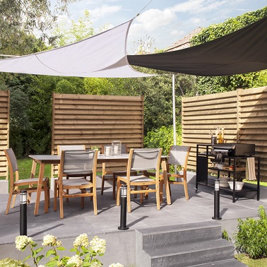 De l'ombre sur la terrasse avec des voiles d'ombrage délicats et pratiques pour l'été. Castorama Pour abriter votre terrasse du soleil facilement et sans vider votre porte-monnaie rien de tel que d’opter pour le voile d’ombrage. Si votre terrasse est indépendante de la maison comme celle-ci, utilisez les poteaux de fixation fournis dans certains kits de toile d’ombrage pour installer votre voile. Néanmoins, si votre terrasse est accolée à votre maison il convient de respecter plusieurs étapes. Tout d’abord mettre la toile à plat au sol et attacher les tire forts à chaque coin avant de les relâcher au maximum. Vous pouvez ensuite monter la toile et stabiliser les tire forts aux mousquetons incrustés sur la façade. Il ne vous reste alors plus qu’à tendre la toile au maximum pour assurer l’esthétisme et l’ombre sur votre terrasse ! Castorama – voile triangle couleur ardoise – Dim : 360 cm. Toile polyester de haute qualité, étanche, 180 gr/m². Prix : 49,99 euros