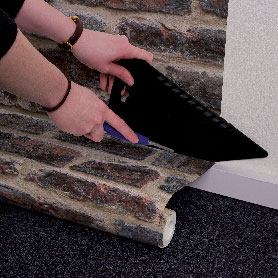 Après avoir posé le papier peint sur le mur, faire la découpe au bas du mur à l'aide  d'une règle et d'un cutter