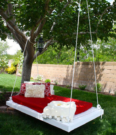 Dans une version sophistiquée, une balancelle de jardin fabriquée avec une palette peinte en blanc, corde blanche et matelas rouge. 
