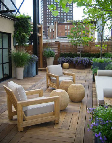 Une terrasse zen qui mise sur le bois pour le sol et le salon de jardin pour faire oublier l'agitation de la ville tout en s'isolant des regards avec une claustra tout le long des murs d'enceinte 