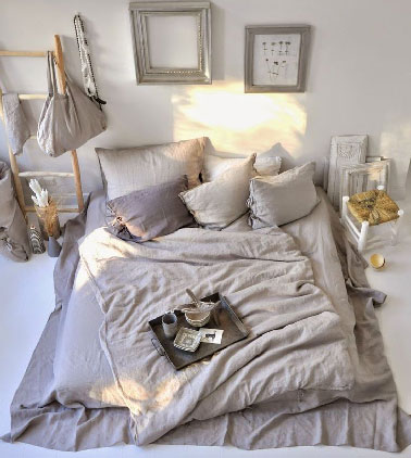 une chambre zen et de rêve pour s'offrir une déco cocooning avec son lit au niveau du sol, les tables de chevet en bois et les tons lin et mordoré de la couette et des coussins  