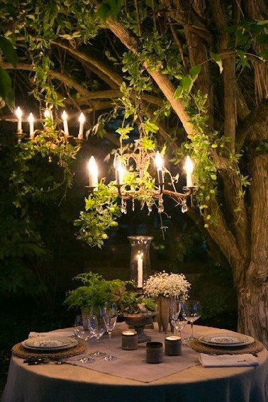 Quoi de plus romantique qu'un dîner en tête à tête dans le jardin que de suspendre 2 lustres dans un arbre et d'avoir un photophore sur la table ronde !