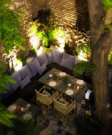 Pour éclairer le coin repas sur la terrasse, mettre des spots aux bas des hauts murs de pierres s'avère une bonne idée pour diffuser une lumière douce sur la table et y voir suffisamment clair. 