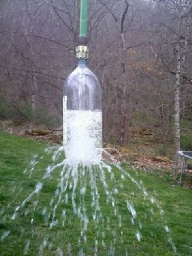 Il fallait y penser ! installer une douche d'extérieur avec une bouteille plastique transformée en pommeau et fixée au bout du tuyau d'arrosage suspendu à un arbre. une idée futée pour se rafraichir sous une douche de jardin construite avec les moyens du bord !