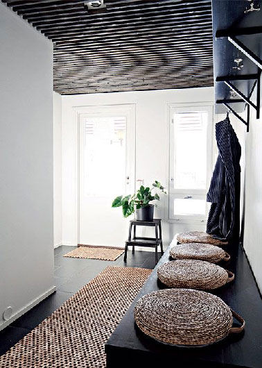 Style épuré, tapis en sisal, peinture blanche, sol noir, un ensemble d'éléments assurant une déco zen à ce couloir d'entrée de maison contemporaine. 
